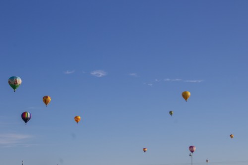 A clear blue sky filled with colorful hot air balloons floating gently above.