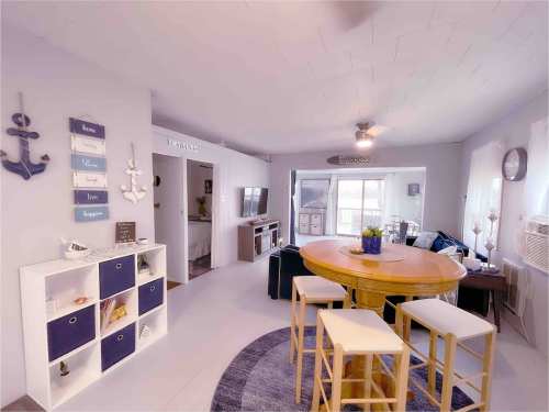 Cozy living space with a round table, chairs, and nautical decor, featuring light colors and a welcoming atmosphere.