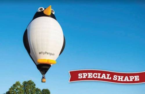 A large penguin-shaped hot air balloon floats against a blue sky, with a banner reading "SPECIAL SHAPE."