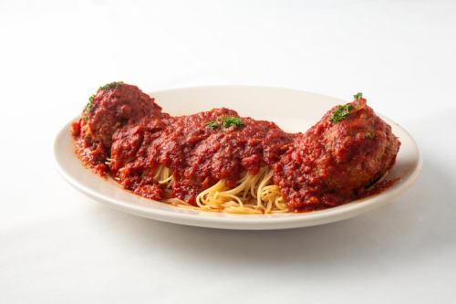 A plate of spaghetti topped with two large meatballs and marinara sauce, garnished with parsley.