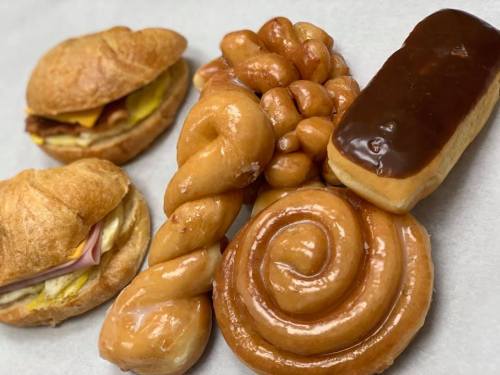 A variety of baked goods including croissants, a twisted pastry, a glazed spiral, and a chocolate-covered donut.
