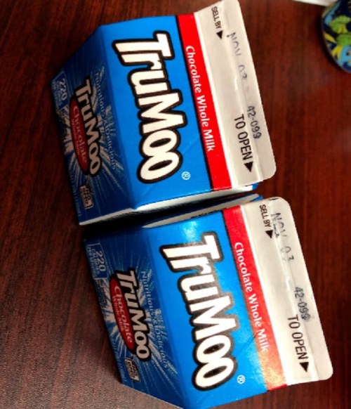 Two cartons of TruMoo chocolate whole milk on a wooden surface.