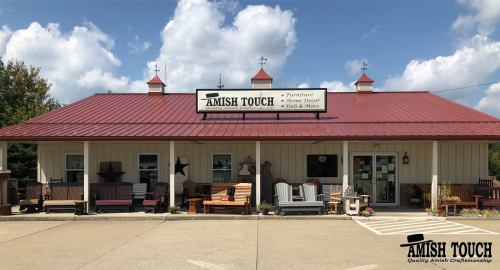 Exterior of "Amish Touch" store featuring furniture and home decor, with a red roof and decorative elements.