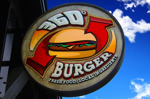 Sign for "360° Burger" featuring a burger graphic, with the tagline "Fresh Food, Local Ingredients" against a blue sky.
