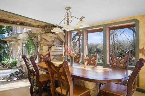 A cozy dining area with a wooden table and butterfly chairs, surrounded by large windows and a natural landscape outside.