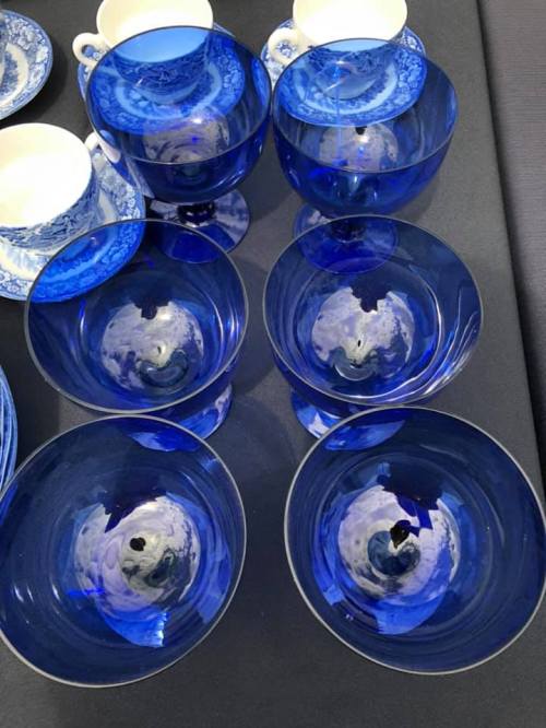 A collection of blue glass bowls and cups arranged on a dark surface.