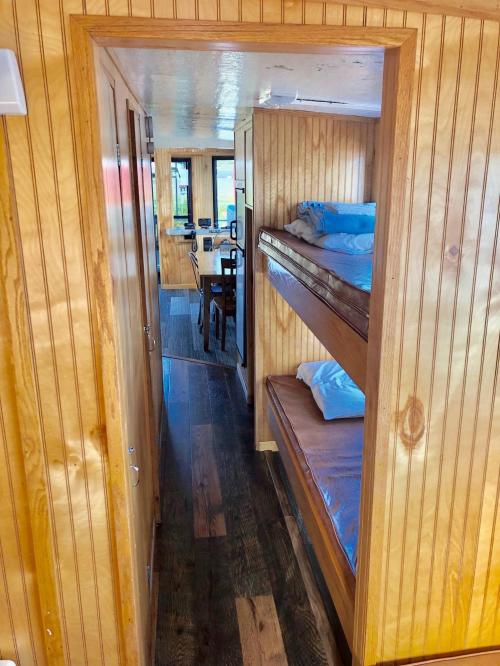 Interior view of a wooden hallway leading to a room with bunk beds and a dining area in the background.