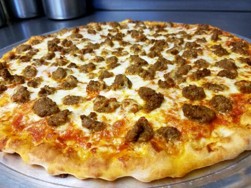 A freshly baked pizza topped with melted cheese and chunks of seasoned ground meat on a golden crust.