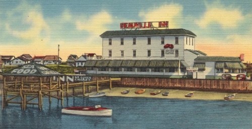 Vintage postcard of Seaville Inn, featuring a waterfront view with boats and a sign for seafood dining.