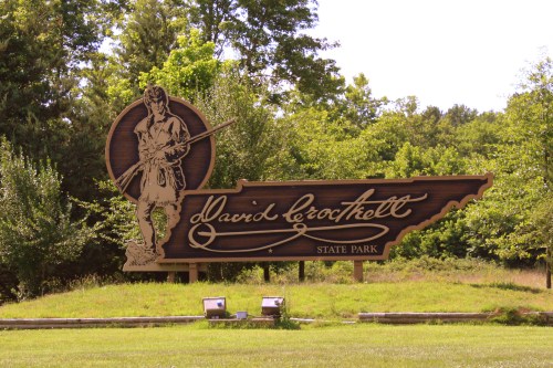 Sign for David Crockett State Park featuring a silhouette of a man with a rifle, surrounded by trees.