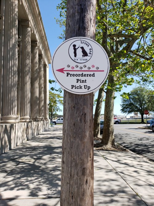 Sign on a wooden post directing to "Preordered Pint Pick Up" for Brown Dog Ice Cream.