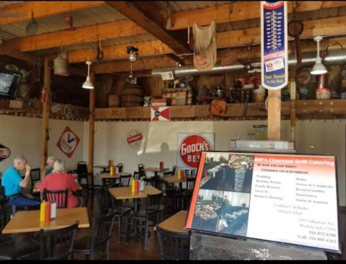 Interior of a casual restaurant with wooden beams, tables, and vintage signs. Two patrons are seated at a table.