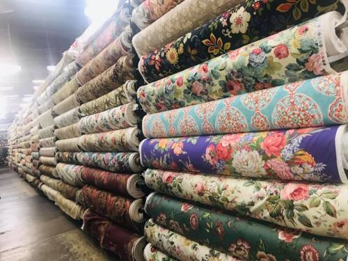 A colorful display of rolled fabric bolts stacked neatly in a fabric store.