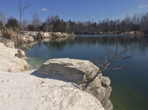 A serene lake surrounded by rocky shores and sparse trees under a clear blue sky.