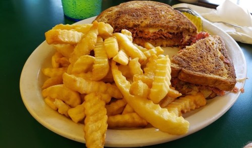 A plate with a toasted sandwich and a side of crinkle-cut fries.