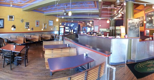 Interior of a casual dining restaurant with wooden benches, colorful walls, and a counter area.