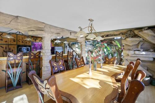 A unique dining area with a large wooden table, decorative chairs, and stone walls adorned with plants.