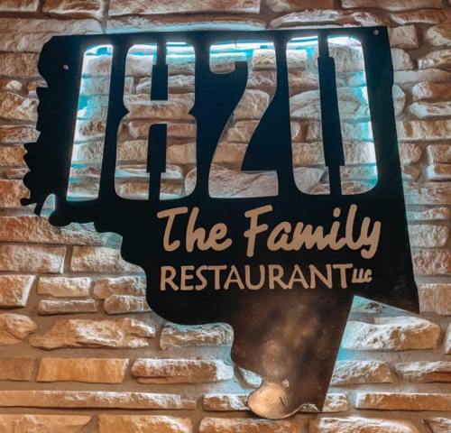 Sign for "1820 The Family Restaurant" with a stylized design against a stone wall background.