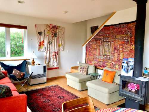 Cozy living room with colorful textiles, a small fireplace, and a mix of seating options, creating a warm atmosphere.