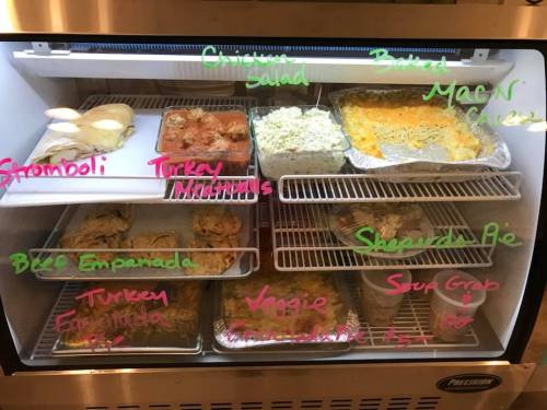 A fridge filled with various prepared dishes, including stromboli, chicken salad, mac and cheese, and shepherd's pie.