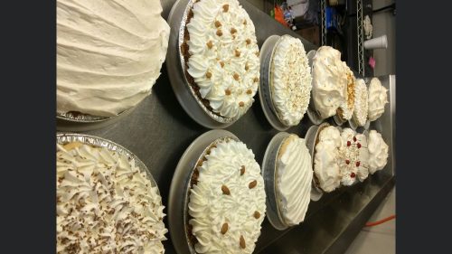 A variety of decorated cream pies with different toppings arranged on a countertop.