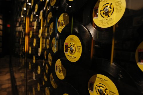 A close-up of vintage vinyl records displayed on a wall, featuring yellow labels and a reflective surface.