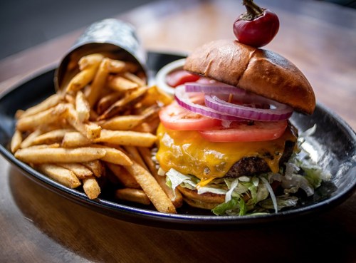 A juicy cheeseburger topped with lettuce, tomato, and onion, served with a side of crispy fries.