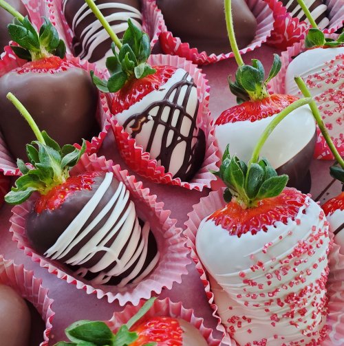 A variety of chocolate-covered strawberries, some drizzled with white chocolate and decorated with sprinkles.