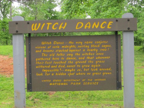 Sign reading "Witch Dance" with a description of local folklore about witches dancing in a forested area.