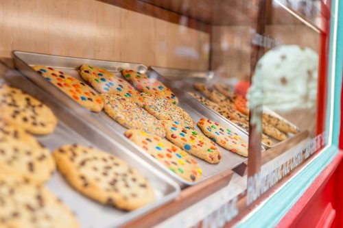A display case filled with colorful cookies, featuring chocolate chips and sprinkles, in a bakery setting.