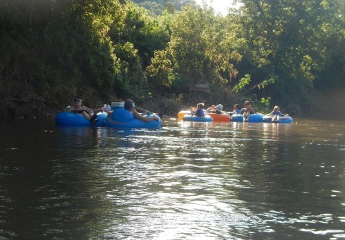 A group of people floating on colorful inner tubes down a calm river surrounded by lush greenery.