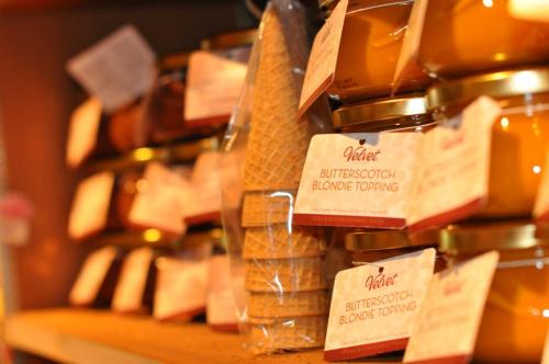 Jars of butterscotch blondie topping on a shelf, with a cone-shaped container in the foreground.
