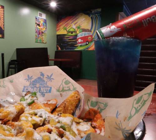 A plate of nachos topped with cheese and jalapeños, alongside a colorful drink in a vibrant restaurant setting.