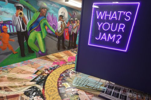 Colorful mural featuring musicians and a neon sign reading "What's Your Jam?" with a vibrant, patterned floor.