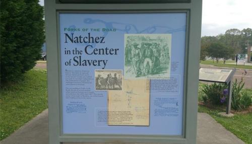 Signage titled "Forks of the Road" detailing Natchez's historical role in slavery, featuring images and text.