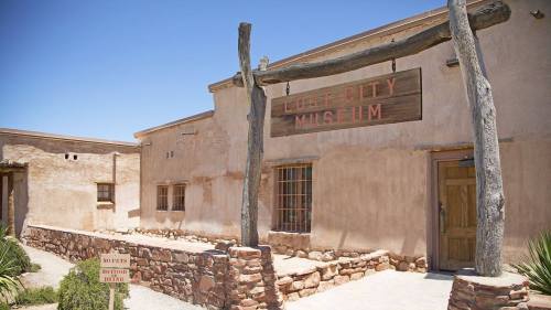 Exterior of the Lost City Museum, featuring adobe-style buildings and a wooden sign, under a clear blue sky.