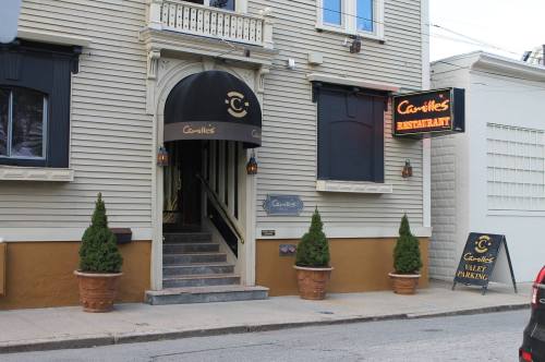 Exterior of Camille's Restaurant featuring a black awning, potted plants, and a valet parking sign.