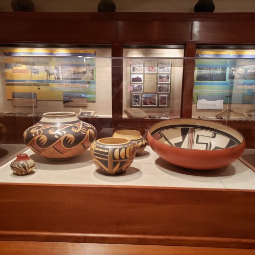 Display of traditional pottery in a museum, featuring various shapes and intricate designs.