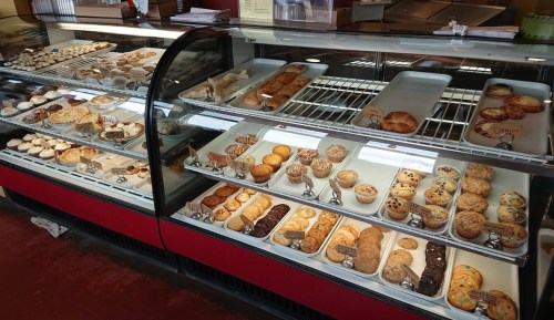 A display case filled with a variety of baked goods, including cookies, pastries, and cupcakes.