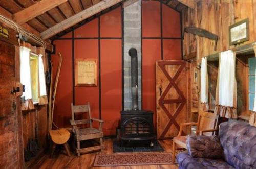 Cozy cabin interior with wooden walls, a wood stove, rustic furniture, and a warm, inviting atmosphere.