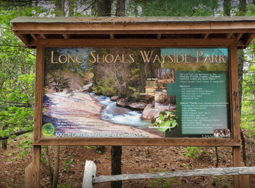 Sign for Long Shoals Wayside Park featuring a river and forest, with information about the park and its sponsors.