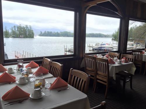 Cozy restaurant interior with tables set for dining, overlooking a serene lake and boats outside.