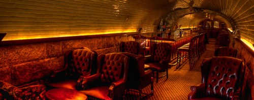 Cozy underground bar with leather chairs, warm lighting, and a stylish ambiance.