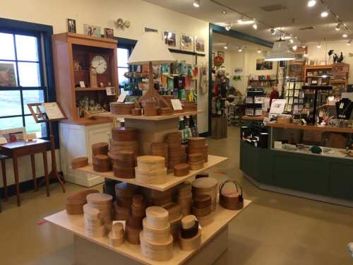 A cozy shop interior featuring wooden containers on display, with various gifts and decor items in the background.