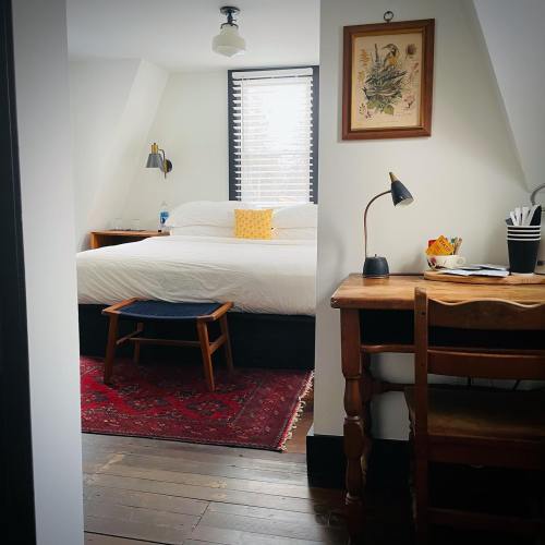 Cozy bedroom with a large bed, a desk, and a rug, featuring natural light and simple decor.