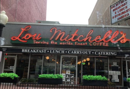 Sign for Lou Mitchell's restaurant, featuring "Serving the world's finest coffee" and offering breakfast, lunch, and catering.