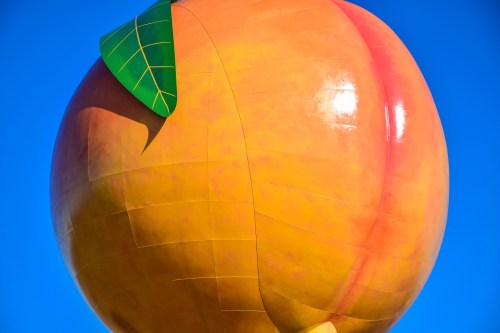 A large, colorful peach-shaped water tower against a clear blue sky.