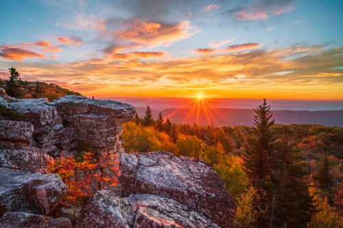 A vibrant sunset over a mountainous landscape, with colorful clouds and rocky foreground.