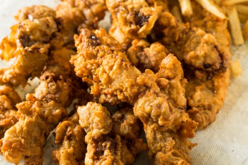 Crispy fried chicken tenders served with golden French fries on a paper-lined plate.