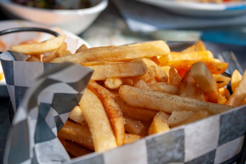 A close-up of a basket filled with golden, crispy French fries, served in a checkered paper liner.